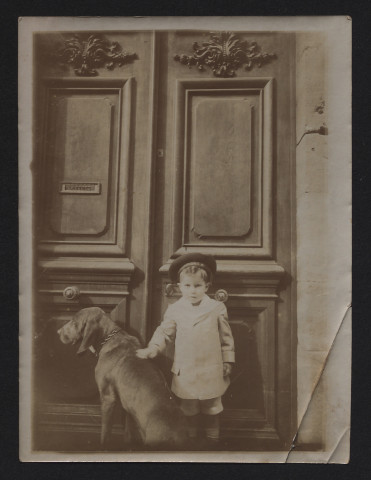 Garçon avec un chien devant une porte d'entrée.