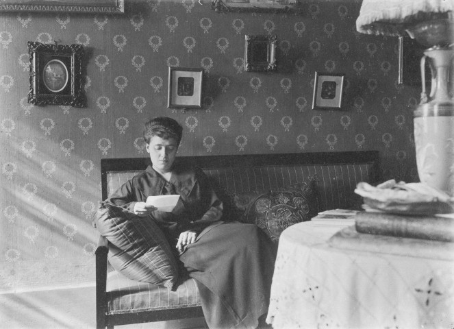 Charols, château de Salettes. - Marthe de Courtois lisant une lettre, assise dans le canapé du salon.