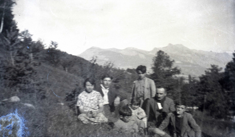 Groupe d'hommes, de femmes et d'enfants posant assis dans l'herbe.