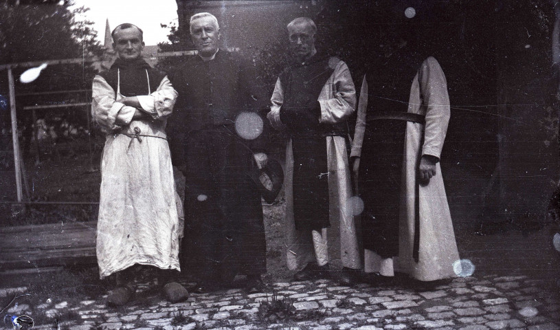 Groupe d'hommes en habit religieux posant debout à l'extérieur.