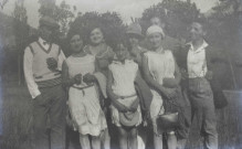 Groupe d'hommes et de femmes posant debout à l'extérieur.