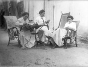 Lieu non identifié. - Madeleine Boudier de Laribal de Boisson, écrivant, Émilie Boudier de Laribal de Boisson, lisant une lettre, et Marthe de Courtois lisant un livre.