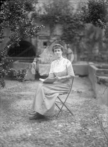 Charols, château de Salettes. - Marthe de Courtois, assise dans une chaise de jardin, un livre entre les mains.