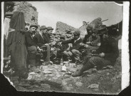 Soldats prenant leur repas parmi les décombres.