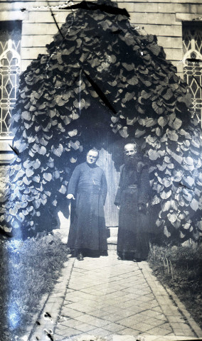 Deux hommes en habit religieux posant debout devant un bâtiment.