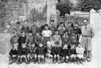 Photographie d'une classe de CP de l'école de garçons et l'instituteur Mr Magnan, dans la cour de l'ancienne cantine, rue du Verger.