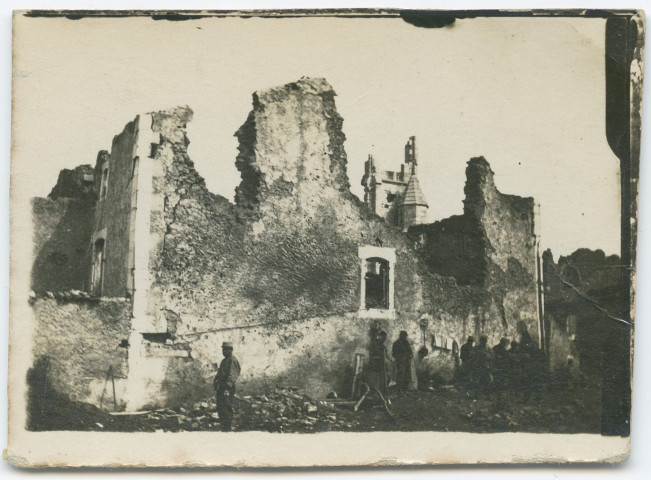 Soldats devant un bâtiment détruit.